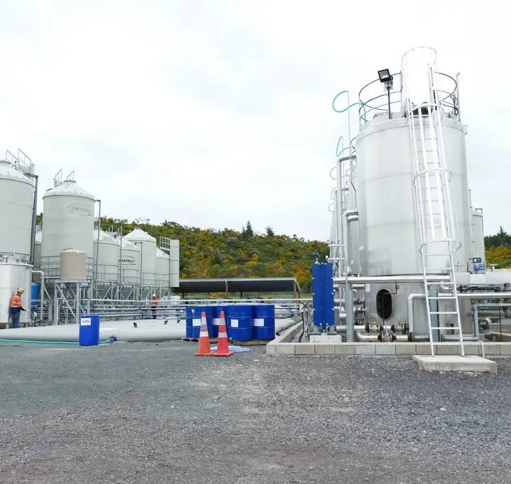 Treatment tanks and process piping at a water treatment plant, with operators on site